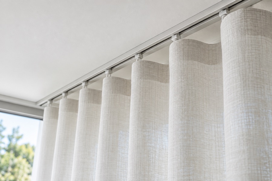 Ceiling-mounted S-fold curtain track with evenly spaced carriers